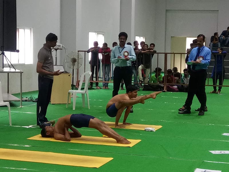 Competitors performing Setu Bandhasana (bridge variation) and Tittibhasana (Firefly arm balance) during state yogasana judging round